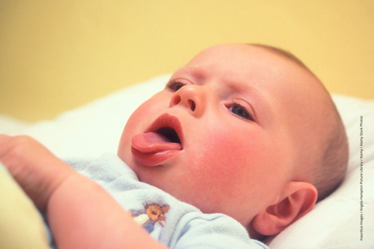 Hustendes Baby liegt in seinem Bettchen.
