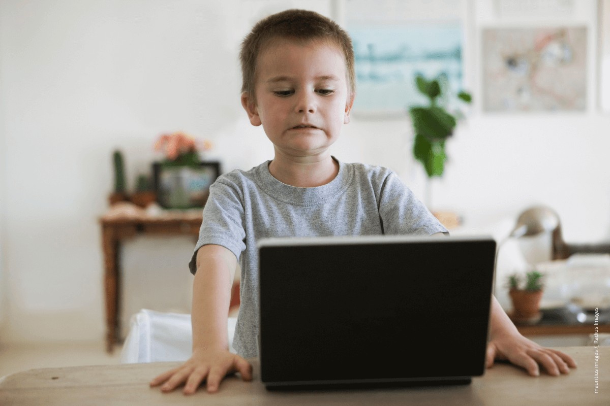Ein Kind schaut sich ein Bild auf einem Laptop an und verzieht sein Gesicht.